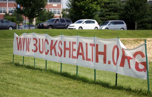 FILE IMAGE - Signs for and against Aria Health Care System sit on opposite sides of Yardley Newtown Road in Lower Makefield near Shady Brook Farm. Here a sign on the south side of Newtown Yardley Road, on the edge of Shady Brook Farm a sign promotes the website of Aria Health Care System. - Steve Gengler / Staff Photographer