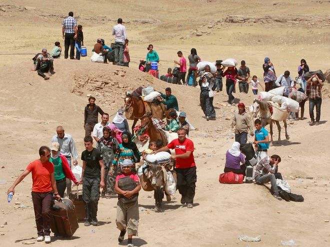 Syrian refugees cross into Iraq at the Peshkhabour border point in Dahuk, 260 miles northwest of Baghdad, Iraq, Tuesday, Aug. 20, 2013.