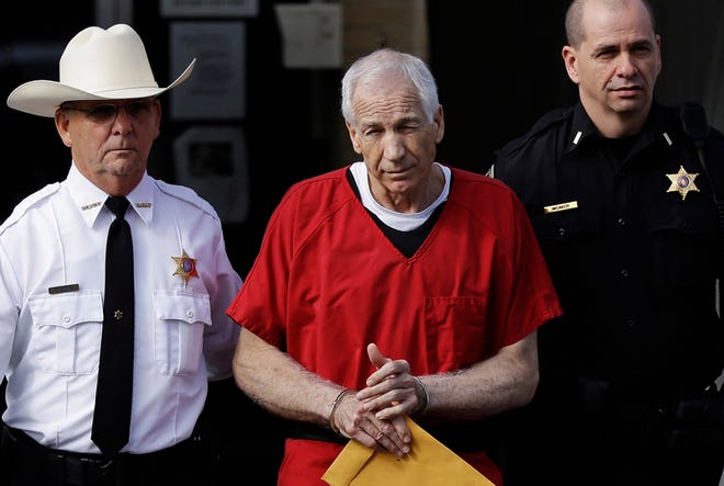 FILE - In this Oct. 9, 2012 file photo, former Penn State University assistant football coach Jerry Sandusky, center, is taken from the Centre County Courthouse by Centre County Sheriff Denny Nau, left, and a deputy, after being sentenced in Bellefonte, Pa. Seven young men, including Jerry Sandusky's adopted son, have finalized deals with Penn State over claims of abuse by the school's former assistant football coach, their lawyer said Friday, Aug. 23, 2013. (AP Photo/Matt Rourke, File)