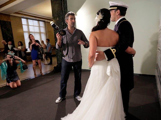 Wedding photographer Goran Veljic poses groom Lt. Lisardo Hernandez and bride Alnair Vivanco, of Oviedo, Spain, before their ceremony inside New York's Office of the City Clerk, Wednesday, Aug. 7.