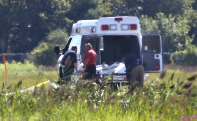Emergency workers place human remains into a Massachusetts medical examiner's vehicle at the site of a small plane crash at Taunton Municipal Airport, in Taunton, Mass., Sunday.
