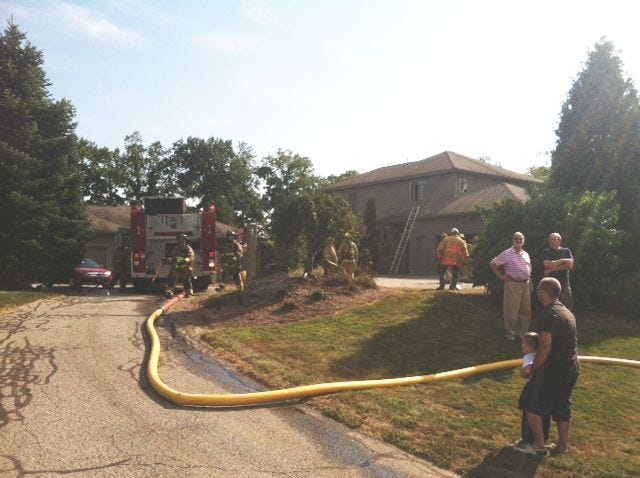 Firefighters work at the scene of a house fire at 221 Cushing Road on Wednesday afternoon. Smoke and flames were reportedly coming from the house.