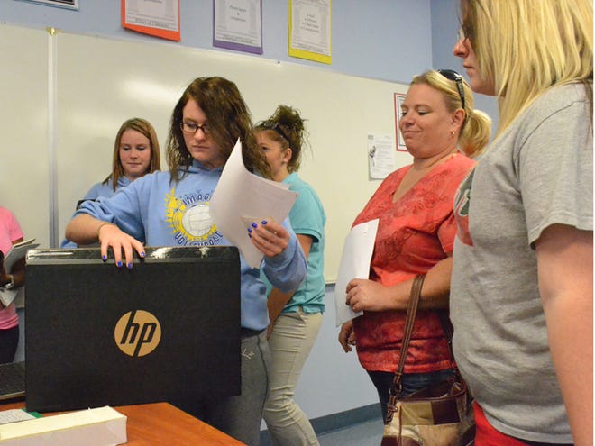 Kayla Browning, 15, picks up a school-issued laptop from Imagine Charter School in North Port. The school gave each high school student one of 275 laptops the school bought for about $30,000.