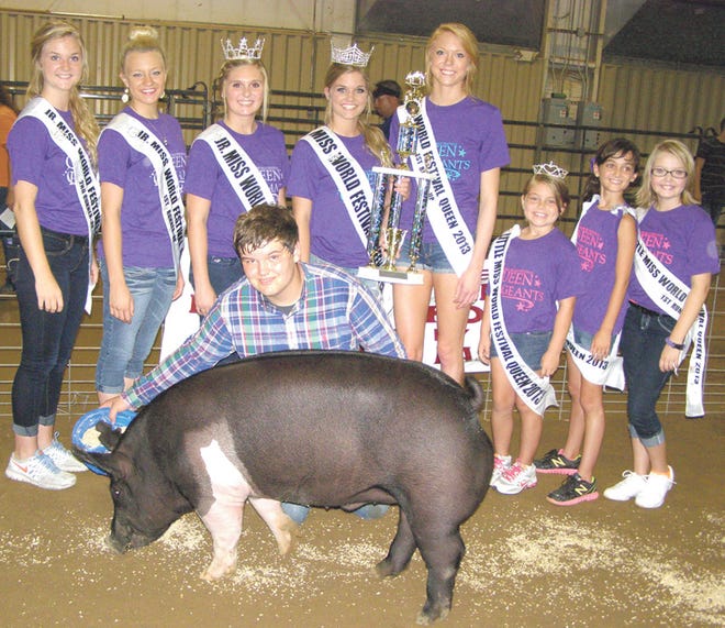 Adam Gradert, of Geneseo, is shown with his 302-pound crossbred barrow which was named reserve grand champion of the Hog Capital Barrow Show held Wednesday night at Black Hawk College East Campus. 2013 Miss World Festival Abigail Brown and her court presented the trophy.