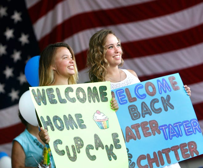 Cheyenne Smith, left, supports her sister Shelby Smith, as the two hold signs while watching Shelby Smith's boyfriend Lance Cpl. Nathan Donahue return to Marine Corps Air Station New River Thursday evening.