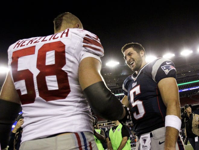 New York Giants middle linebacker Mark Herzlich (58) and New England Patriots quarterback Tim Tebow (5) speak after an NFL preseason football game Thursday, Aug. 29, 2013, in Foxborough, Mass. The Patriots won 28-20. (AP Photo/Mary Schwalm)