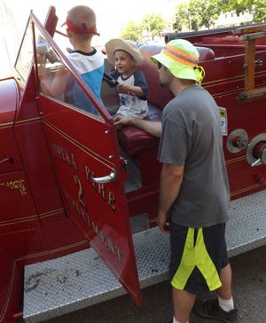 From left, Matthew Wright, 7, and brother Xander Wright, 5, check out a 1940s model American LaFrance antique fire truck with their father George Wright on Saturday afternoon in downtown Topeka at the first annual Touch-A-Truck event.