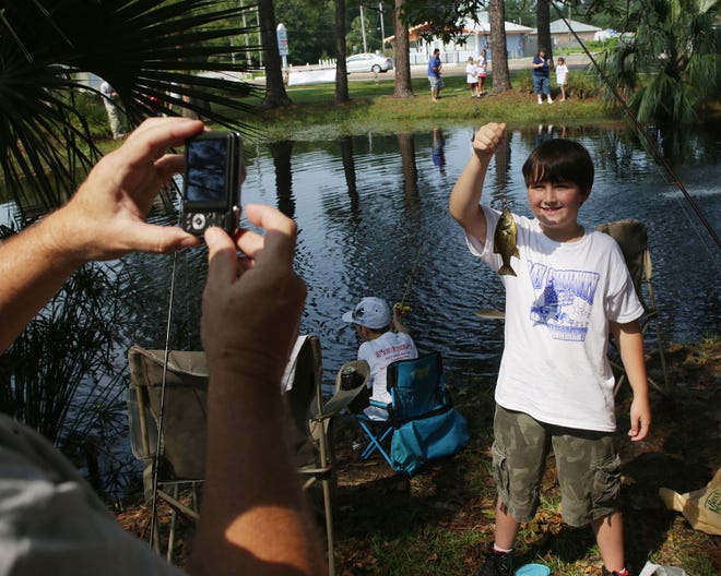 Bradley Hansen, 10, holds up a fish to have a photo taken during a fishing tournament at a Labor Day weekend celebration at Sharon Sheffield Park in Lynn Haven on Saturday.