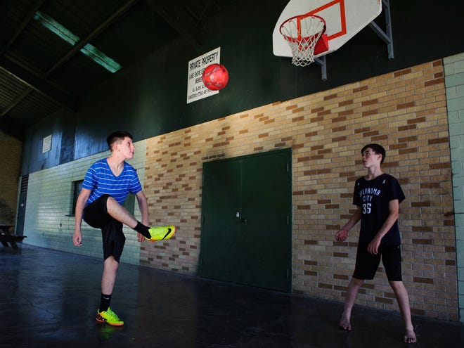 Tycho Wagner, 12, left, kicks a soccer ball to the basket with Quinn Cunningham, 13, Monday at the Hulen Lake shelter