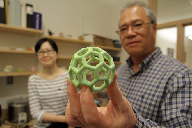 Thursday September 5, 2013 Kingston, RI - Bongsup Cho, Professor of Medical Chemistry at URI, holds a model that was printed with a 3D printer at the URI College of Pharmacy. In background is URI Graduate student Lifang Xu. The college is looking for ways to provide the 3D printing services to local businesses.