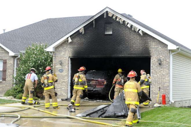 Columbia firefighters examine the scene of a garage fire Thursday at 4103 Eagle View Court. No one was injured, but a Ford Explorer and a boat were destroyed.