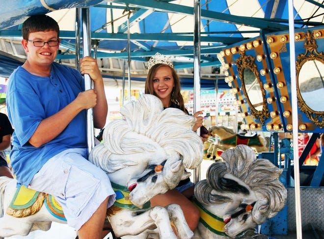 Chris Lesones, 20, of Monmouth, smiles along with Warren County Prime Beef Festival Princess Chloe Larson while riding the carousel during Special Person's Day Friday afternoon. ANNIE PITTMAN/REVIEW ATLAS