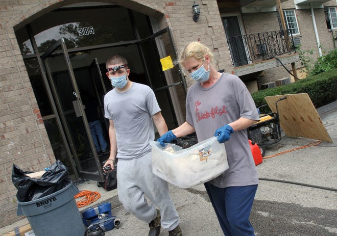 Denise Hartsock, mother of Julie England, and Julie's fiancé, Jeremy Sullivan, who were living with Julie at Dean Estates, carry out some of their salvageable belongings on Thursday.