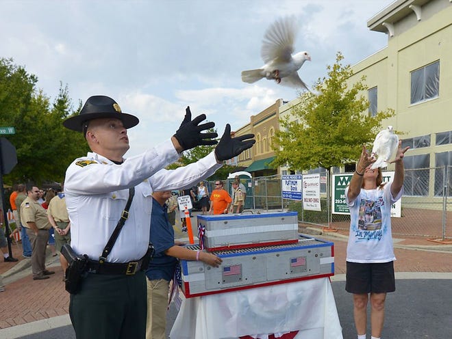 Polk County Sheriff's deputy Doug Zulker and Ronna Jackson release doves prior to the Freedom Walk during Honoring Our Heroes-Remembering the Day held Saturday evening in Winter Haven's Central Park.