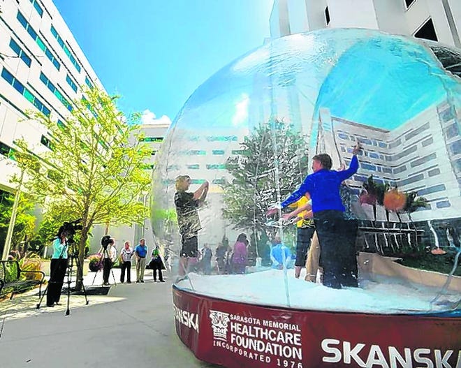 Sarasota Memorial Hospital staff and volunteers pose for photos inside a 
giant snow globe during a media preview of the new Courtyard Tower on 
Friday. The hospital has invited the public to a grand opening ceremony 
today. STAFF PHOTO / MIKE LANG