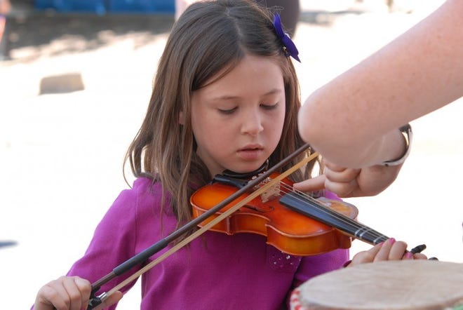 Six-year old Eva Mussari of Doylestown tries her hand playing a one-tenth violin at The Conservatory booth during the Doylestown Arts Festival in Doylestown, a two-day event that has artists and live music, Saturday, Sept. 7, 2013. (Catherine Meredith/freelance)no internet sales