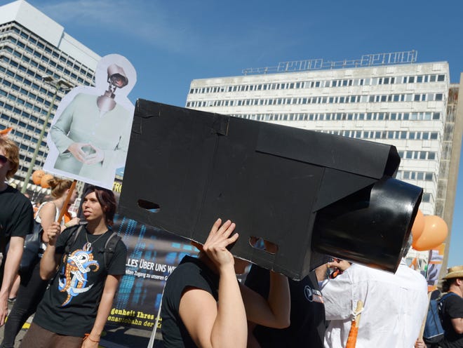 In this picture taken Sept. 7, 2013, a woman protests with a selfmade surveillance camera on her head during the demonstration 'in Berlin, Germany. German news weekly Der Spiegel reports Sunday Sept. 8, 2013 that the U.S. National Security Agency can access users' data on all major smartphones. The magazine cites internal documents from the NSA and its British counterpart GCHQ in which the agencies describe setting up dedicated teams to crack protective measures on iPhones, BlackBerry and Android devices. This data includes contacts, call lists, SMS traffic, notes and location data. (AP Photo/dpa,Rainer Jensen)