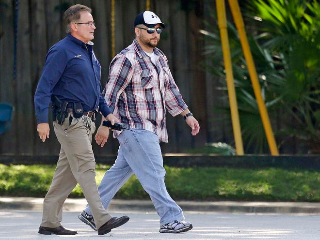 George Zimmerman, right, is escorted to a home by a Lake Mary police officer, Monday, Sept. 9, 2013, in Lake Mary, Fla., after a domestic incident in the neighborhood where Zimmerman and his wife Shellie had lived during his murder trial. Zimmerman's wife says on a 911 call that her estranged husband punched her father in the nose, grabbed an iPad out of her hand and smashed it and threatened them both with a gun. (AP PHOTO)