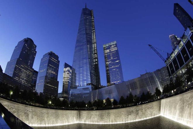 In this image made with a fisheye lens, One World Trade Center, center, rises above waterfalls at the National September 11 Memorial and Museum, Sunday, Sept. 8, 2013, in New York. Twelve years after terrorists destroyed the old World Trade Center, the new World Trade Center is becoming a reality, with a museum commemorating the attacks and two office towers where thousands of people will work set to open within the next year. (AP Photo/Mark Lennihan)