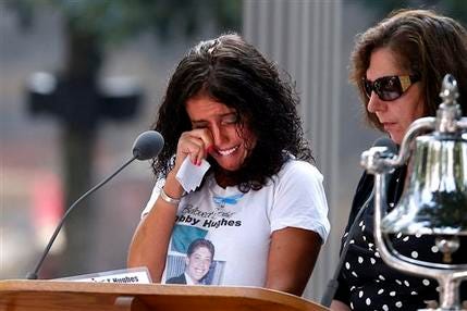 A woman wipes her eyes after reading the name of her brother, Bobby Hughes, as friends and relatives of the victims of the 9/11 terrorist attacks gather at the National September 11 Memorial at the World Trade Center site, Wednesday, Sept. 11, 2013, for a ceremony marking the 12th anniversary of the attacks in New York.