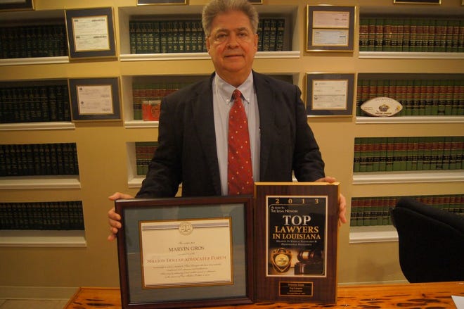 Attorney Marvin Gros stands with his two earned plaques welcoming him to the Million Dollar Advocates Forum and awarding him as a Top Lawyer in Louisiana for Highest Ethical Standards and Professional Excellence for 2013.