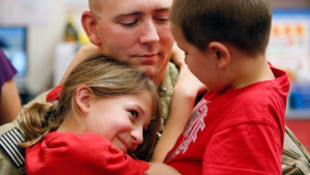 US Army helicopter mechanic Mike Fiber hugs his kids after surprising them at school.