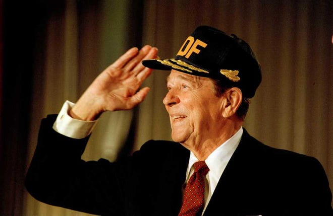 U.S. President Ronald Reagan smiles and salutes as he tries on a hat presented to him at the Keflavik air base, Oct. 13, 1986. The president was leaving the NATO base on his way home to Washington from his meetings in Iceland with Soviet leader Mikhail Gorbachev. (AP Photo/Scott Stewart)