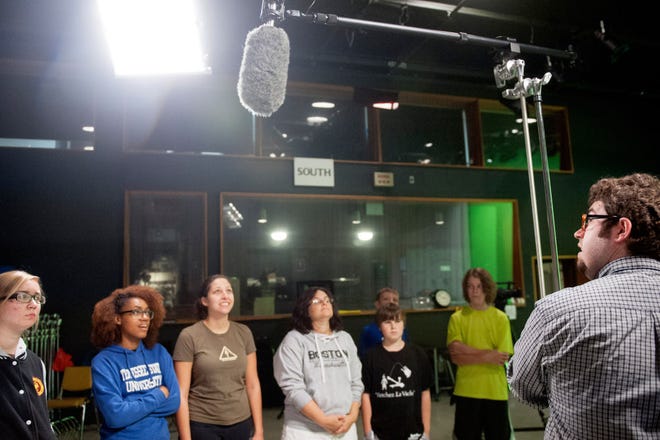 Columbia Access Television Chief Engineer Jimmy Moore, right, instructs students on how to operate a boom microphone stand Thursday during CAT-TV’s studio production class at the CAT-TV studios at Stephens College.