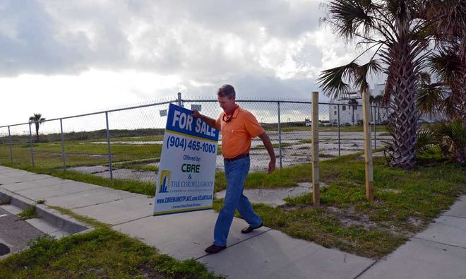 Photos by Bob.Mack@jacksonville.com Cord Butler, principal at The Cordell Group, takes down the For Sale sign from the northwest corner of the Jacksonville Beach property. Developers have bought the block of Jacksonville Beach oceanfront, but so far they haven't announced their definite plans.