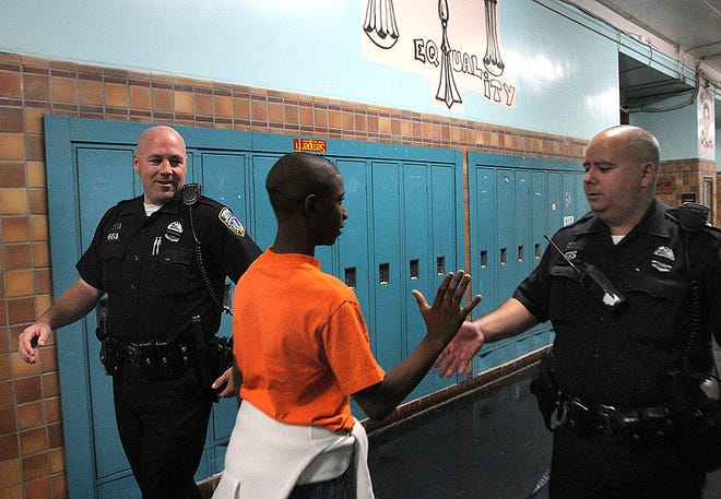 Providence Police Officers Derek Shields, left, and Jeff Richards greet Mt. Pleasant freshman Maurice Johnson in the hall as they patrol Mt. Pleasant High School where they are school resource officers.