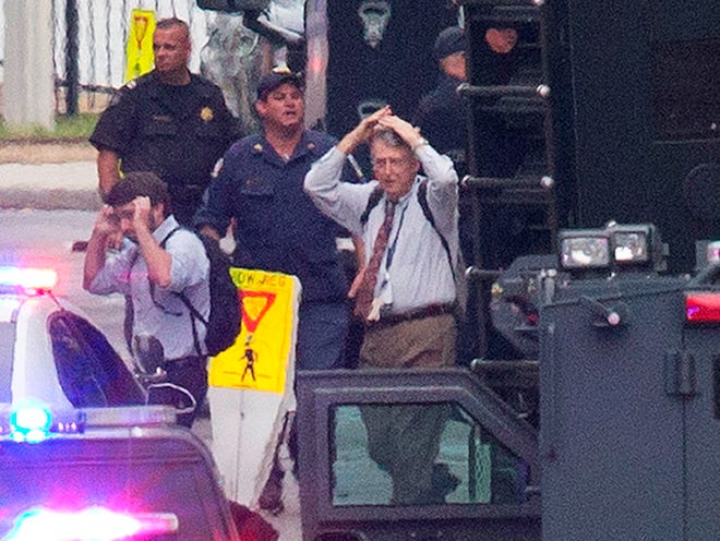 People hold their hands to their heads as they are escorted out of the building where a deadly shooting rampage occurred at the Washington Navy Yard in Washington Monday. One shooter was killed, but police said they were looking for another possible gunman wearing military-style uniforms. (AP Photo/Jacquelyn Martin)