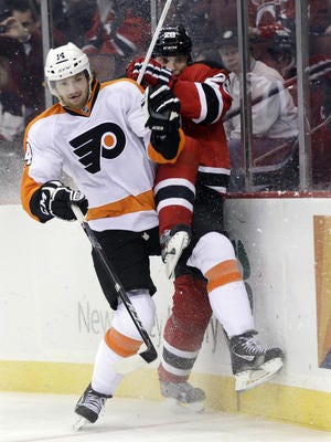 Sean Couturier (left) of the Flyers checks New Jersey's Anton Volchenkov.