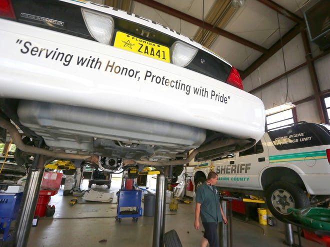 Mechanic Nathan Johnson finishes some work on an older evidence vehicle while a high-mileage patrol car gets rear end work at the Sheriff's Office motor pool in Ocala in this July 11, 2013 file photo.