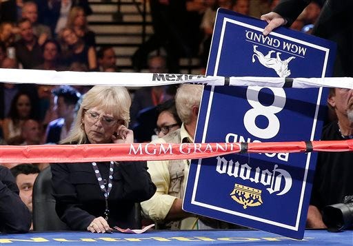 In this photo taken Saturday, Sept. 14, 2012, boxing judge Cynthia C.J. Ross, left, waits to hand her scorecard to the referee after the seventh round of the fight between Canelo Alvarez and Floyd Mayweather Jr. in Las Vegas. Ross is temporarily stepping away from the ring after drawing widespread criticism for scoring the fight a draw when two other judges scored Mayweather the clear winner.