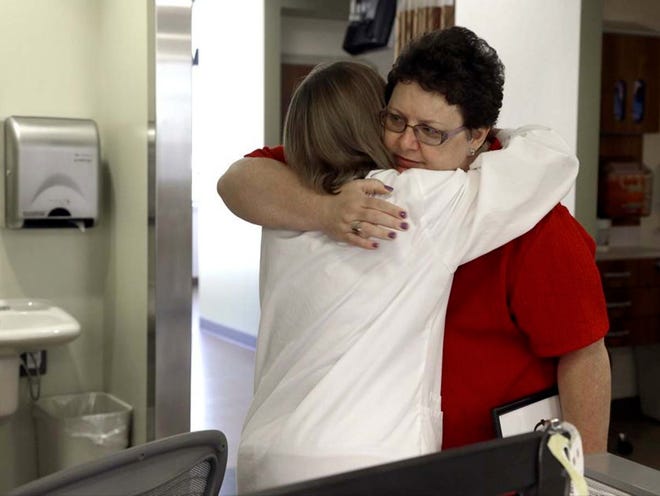 Tracy Smith, right, hugs oncology nurse Ellen Parks during a visit at Duke Cancer Center in Durham, N.C. Smith was treated at Duke in 2011 for breast cancer. Doctors gave her full chemotherapy doses based on her weight. She has been cancer-free since finishing the treatment. 
(Gerry Broome | THE ASSOCIATED PRESS)