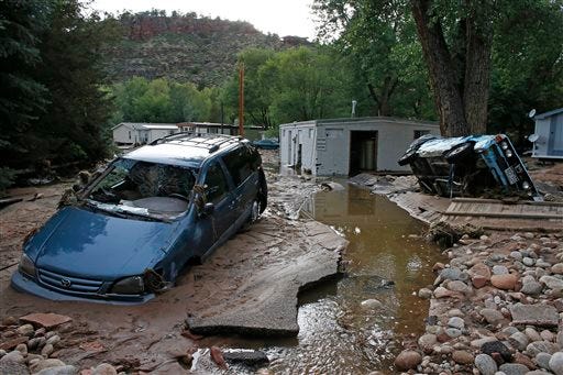 Cars lay mired in mud deposited by floods in Lyons, Colo., Friday Sept. 13, 2013. Days of heavy rains and flash floods which washed out the town's bridges and destroyed the electrical and sanitation infrastructure have left many Lyons residents stranded with minimal access to help, and sectioned off the town into several pieces not reachable one to the other.