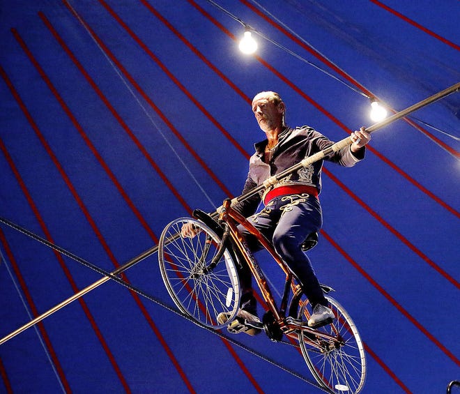 Circus performer Jim Decker uses a 19- foot pole to balance himself on a bicycle as he rides across a tightrope stretched 20 feet above the ground. Photo by Jim Beckel, The Oklahoman. Jim Beckel - THE OKLAHOMAN