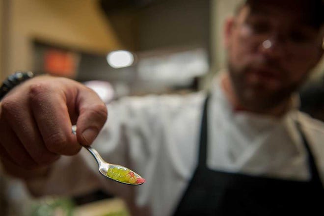Patrick Gilpin, the executive chef at Blue Turtle Bistro, holds a spoonful of spherified melon and cucumber made through a food science process called spherification.