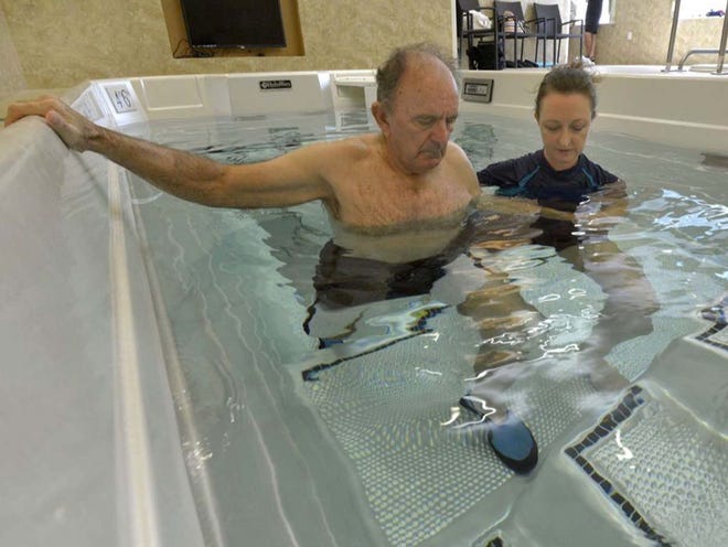 George Cutsail,  a total knee replacement patient, works with Ané Conradie, an aquatic therapist, doing knee bends in one of the two therapy pools at Spring Lake Rehabilitation Center in Winter Haven.