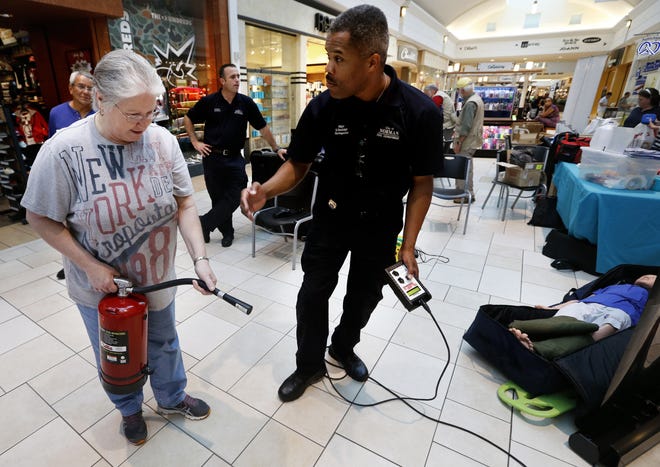 Maj. David Randolph of the Norman Fire Department shows Alice Rodriguez how to use a fire extinguisher during a community preparedness fair at Sooner Mall. PHOTO BY STEVE SISNEY, THE OKLAHOMAN STEVE SISNEY