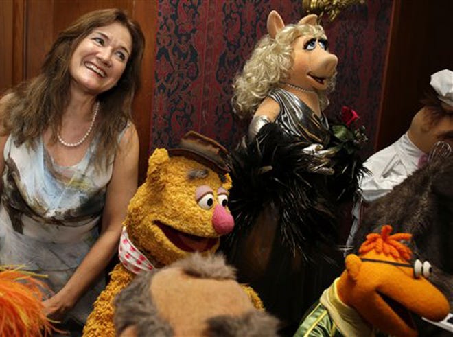 Cheryl Henson, daughter of Jim Henson, left, is surrounded by "muppets" after donating additional Jim Henson objects to the Smithsonian's National Museum of American History, including, from left, Fozzie Bear, Miss Piggy, and Scooter, from The Muppet Show, during a ceremony at the Smithsonian's National Museum of American History in Washington, Tuesday, Sept. 24, 2013. Miss Piggy is finally joining Kermit the Frog in the Smithsonian Institution’s collection of Jim Henson’s Muppets, and Bert and Ernie will have a place in history, too. Henson’s daughter, Cheryl Henson, is donating 20 more puppets and props to the National Museum of American History.