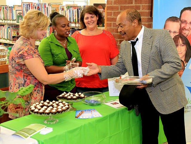 TIMES RECORD FILE PHOTO / Sandy Pippin, from left, Hazel Douglas and Patricia Ihle, representing the Single Parent Scholarship Fund, offer Leon Thompson one of their chocolate samplings during 2012’s annual Friends of The Library Chocolate Festival. This year’s event, slated for Sunday at the Dallas branch of the Fort Smith Public Library, will feature local clubs, businesses, individuals and organizations gathered to sell chocolate baked goods and sweets, with all proceeds benefiting the Friends of the Library for special materials and programs at the libraries.