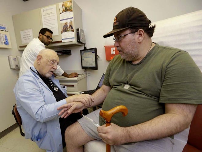 Dr. Arnold Oper, 83, talks with patient Jose Cabrera, 51, who is uninsured, Wednesday at the Doris Isen Health Center in Cutler Bay as physician's assistant Shamiyaaz Jauhari looks on. Next week, Florida residents can start enrolling for health coverage under the Affordable Care Act.