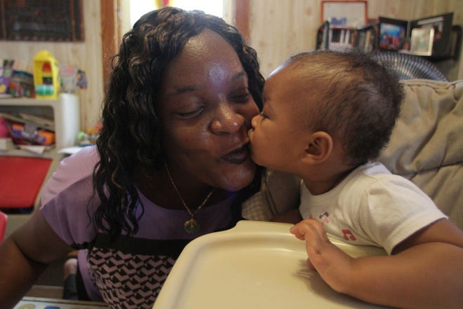 Marie Green gets a kiss from Analise Dummett, 1, who is under her care at her home on Unit Street in Providence.