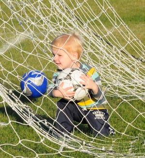 Alex VanDuren, 3, gets a soccer ball out of the net Tuesday during the city of Holland's smart soccer soccer program.