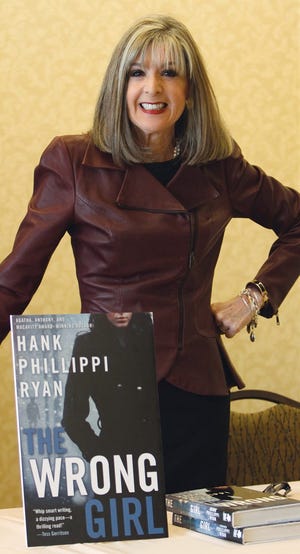 Hank Phillippi Ryan stands for photos with her new book, "The Wrong Girl," before addressing guests at the Connecting Women Leaders luncheon offered by the Milford Area Chamber of Commerce at the Doubletree Hotel on Friday afternoon.