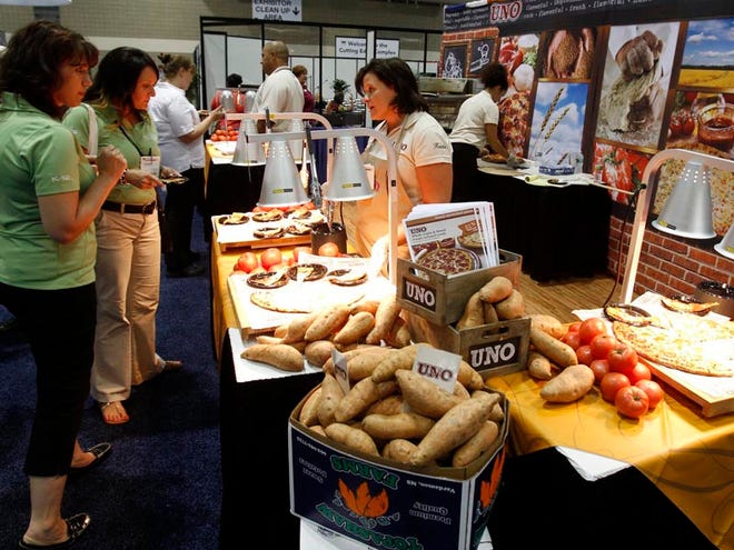Pizza with sweet potato infused crust was being served at the Uno Foods booth, July 15, 2013, at the School Nutrition Association national convention in Bartle Hall in Kansas City, Missouri. Kristin Kopke (right) explained the nutritional value of the pizza.