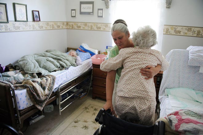 Debora Urquidez gets her aunt Jacqulynn Nance, 87, into her wheelchair as her mother, Jo Ann Gelofsack, 81, lies in bed Sept. 19. Urquidez takes care of both women, who have dementia, at her home in east Columbia.