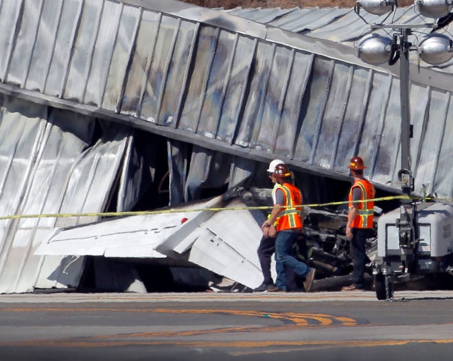 Investigators stand near a hanger at the site of a plane crash in Santa Monica, Calif. Monday, Sept. 30, 2013. Investigators were awaiting the arrival Monday of a crane at Santa Monica Municipal Airport where a private jet crashed into a hangar after landing on Sunday, but they didn't expect to find any survivors. Santa Monica-based Morley Construction company CEO Mark Benjamin and his son, Luke Benjamin, were apparently on the twin-engine Cessna Citation that crashed Sunday evening, Morley Construction Vice President Charles Muttillo told The Associated Press. (AP Photo/Nick Ut)