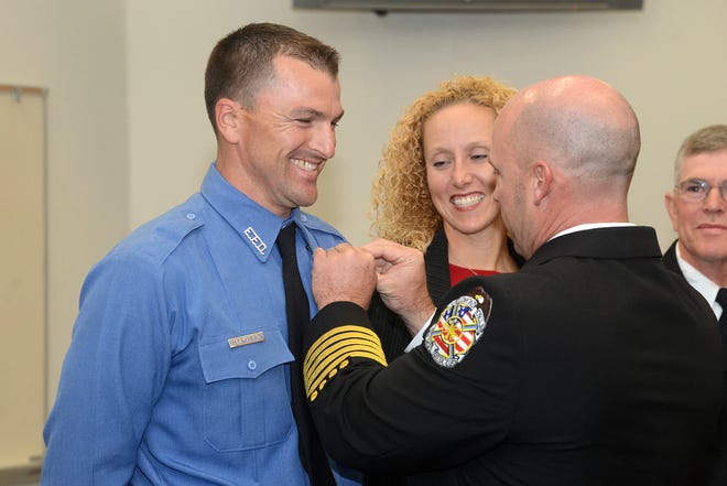 Edmond fire academy graduate Craig Williamson receives his badge from Fire Chief Jake Rhoades as Williamson's wife, Sabrina, looks on. The graduation of nine new firefighters was held at Station 5 on Friday. PHOTO BY DAVID FAYTINGER, FOR THE OKLAhOMAN